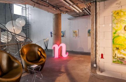 Nhow Berlin Hotel lobby. A gay-friendly hotel with a modern design, featuring lounge chairs, art, and a pink n logo. Unique hotel for gay travelers.