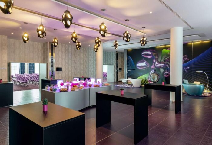 Nhow Berlin Hotel's lobby. Gay-friendly hotel with unique design, modern furniture, and stylish lighting. Buffet with snacks. Perfect for gay travel.