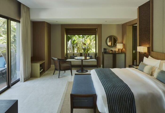 Nirjhara Bali gay-friendly hotel room. King bed, sofa, table, and balcony with jungle view. Luxury accommodations for gay travelers.