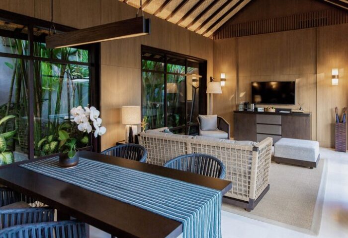 Nirjhara Bali gay-friendly hotel suite. Interior of a luxury villa with dining area, living room, and lush green views. Bali gay travel.