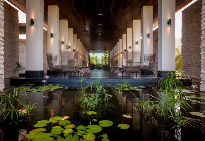Nizuc Resort & Spa's gay-friendly design: an inviting outdoor lounge area with chairs, columns, and a serene pond with lily pads.