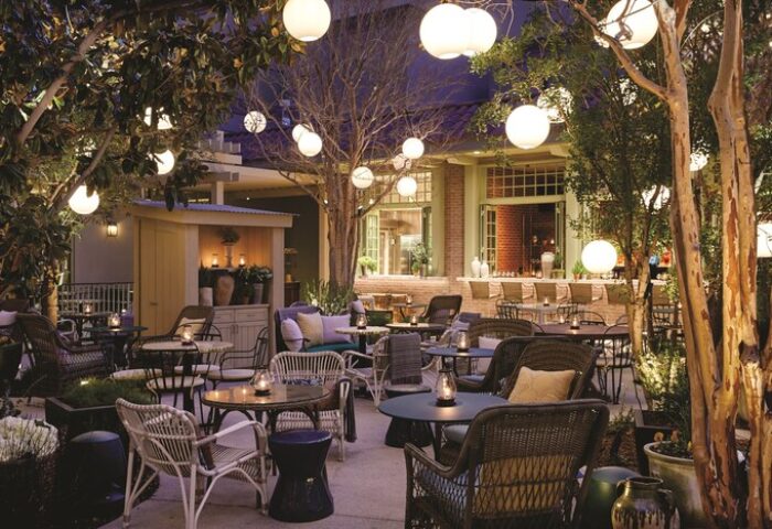 Gay-Friendly NoMad Las Vegas hotel outdoor patio. Tables and chairs under trees with globe lights. A perfect spot for gay travelers.