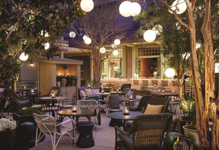 Gay-Friendly NoMad Las Vegas hotel outdoor patio. Tables and chairs under trees with globe lights. A perfect spot for gay travelers.