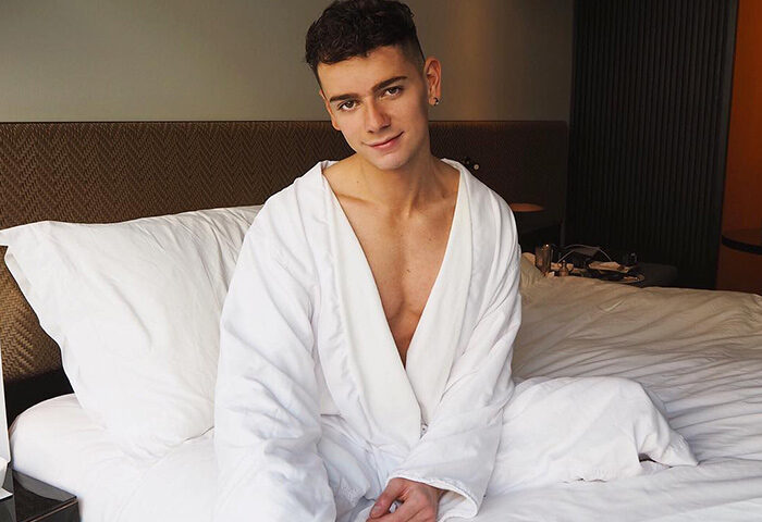 Gay-friendly Nobu Hotel Shoreditch: Man in robe sitting on bed. Pet-friendly hotel offers luxury for gay travelers in Shoreditch, London.
