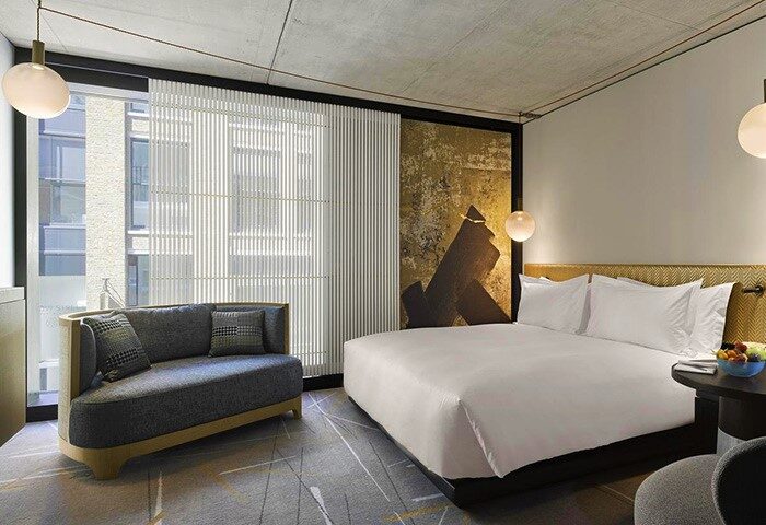 Nobu Hotel Shoreditch room. Gay-friendly, pet-friendly hotel with a modern design, featuring a bed, couch, and stylish decor. Ideal for gay travel.