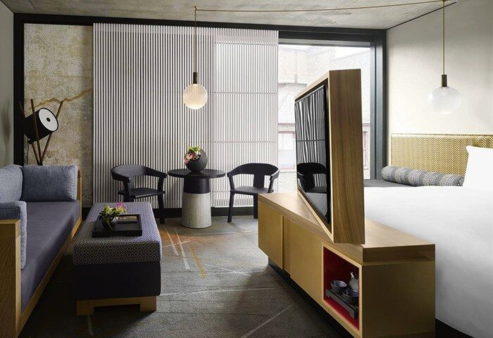 Nobu Hotel Shoreditch room. Gay-friendly, pet-friendly hotel with modern decor, seating area, and a rotating TV stand. Stylish design.