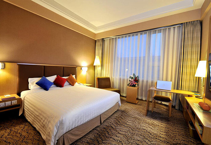 Novotel Beijing Xinqiao gay-friendly hotel room. Bed with colorful pillows, desk, and chair. Comfortable stay for gay travelers in Beijing.