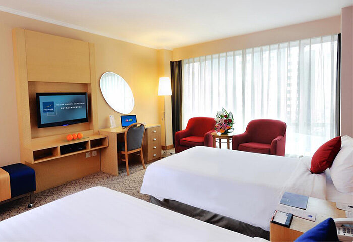 Novotel Beijing Xinqiao gay-friendly hotel room. Twin beds, desk with laptop, TV, and red armchairs. Comfortable stay for gay travelers in Beijing.