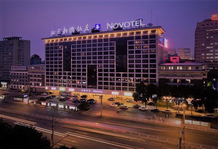 Novotel Beijing Xinqiao, a gay-friendly hotel in Beijing, China. Exterior view of the hotel at night with city lights and traffic. Modern architecture.