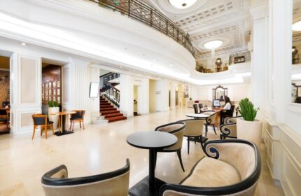 Novotel Budapest Centrum Hotel's lobby. This gay-friendly hotel features elegant seating, a grand staircase, and a welcoming reception area.