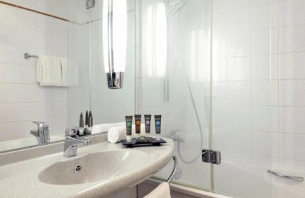Bathroom at Novotel Budapest Centrum Hotel, a gay-friendly hotel. Sink, amenities, shower, and white tiles. Ideal for gay travel in Budapest.
