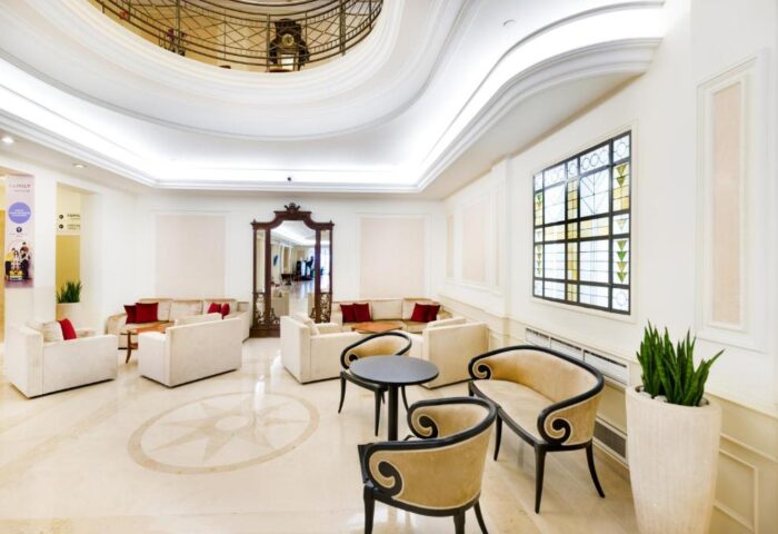 Novotel Budapest Centrum Hotel lobby. Gay-friendly hotel with seating areas, ornate mirror, and decorative window. Elegant design.