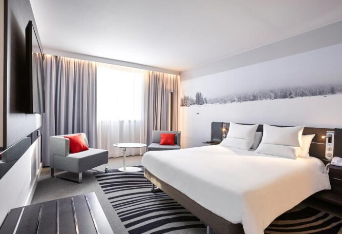 Novotel London Waterloo Hotel bedroom. Gay-friendly hotel room with bed, chairs, and a snowy mural. Modern design for comfortable stay.