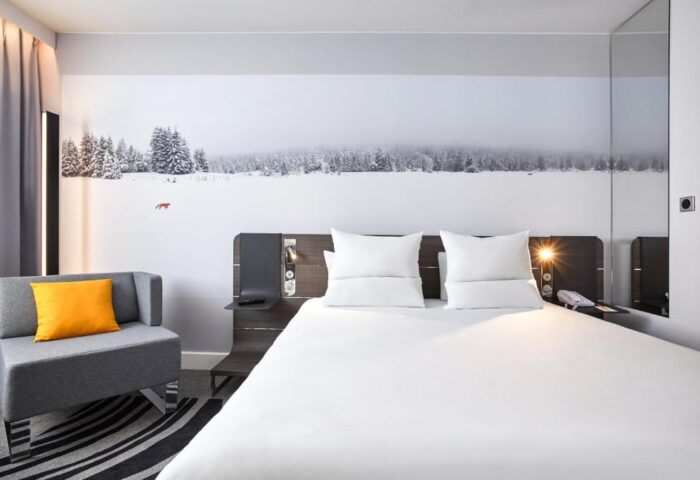 Novotel London Waterloo Hotel room. Modern design, white linens, snow scene wall art. Gay-friendly hotel option for LGBTQ+ travelers.