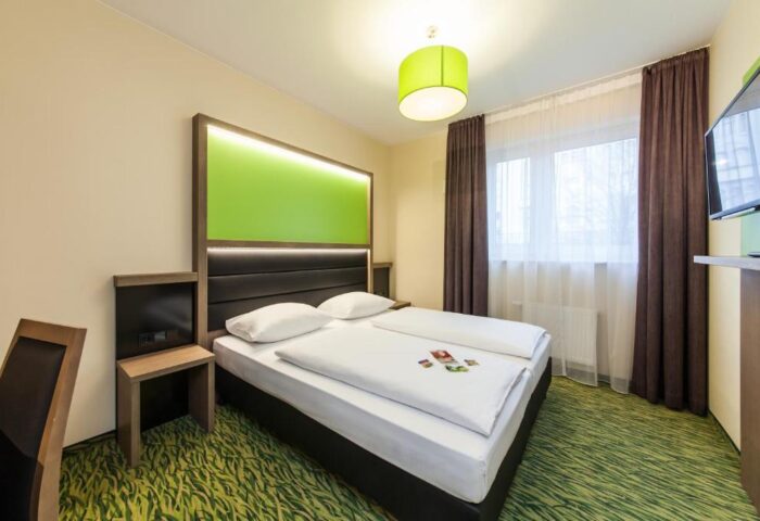 Bedroom at Novum Hotel Aldea Berlin Zentrum, a gay-friendly hotel. Modern design with green accents, comfortable bed, and natural light. #gaytravel