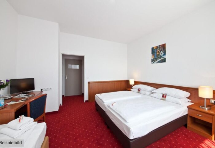 Gay-Friendly Novum Hotel Aldea Berlin Zentrum room. Double bed, desk, TV, red carpet. A great choice for gay travelers in Berlin.