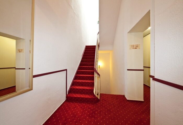 Novum Hotel Leonet Köln Altstadt staircase. Red carpeted stairs in this gay-friendly hotel. Perfect for gay travel in Cologne, Germany.
