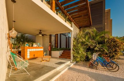 O' Tulum Boutique Hotel's entrance. Adults-only, gay-friendly hotel in Tulum, Mexico. Reception area, bikes, and tropical plants.
