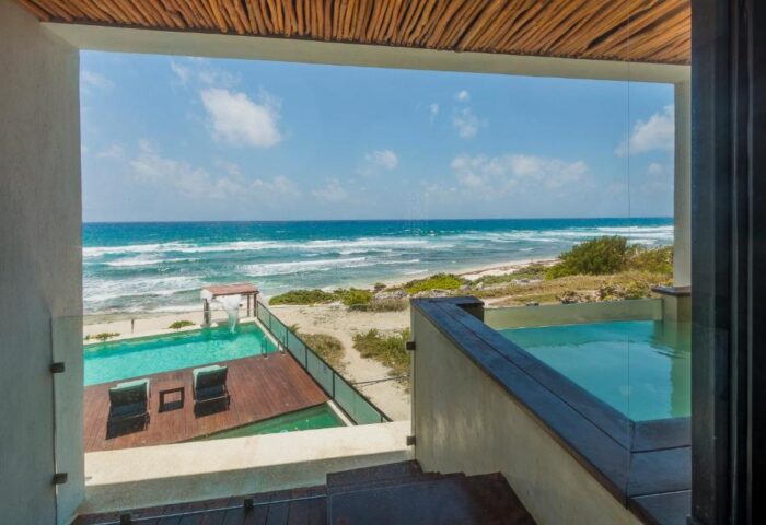 Ocean view from O' Tulum Boutique Hotel, an adults-only, gay-friendly hotel. Pools, beach, and blue sky provide a relaxing vacation vibe.