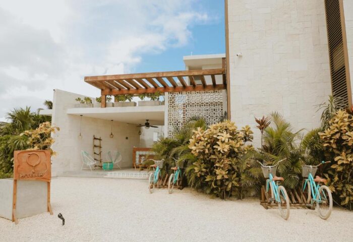 O' Tulum Boutique Hotel adults-only exterior. Gay-friendly hotel with bikes, plants, and modern design. Tulum, Mexico travel destination.