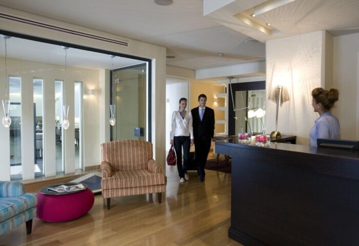 O&B Athens Boutique Hotel lobby. Guests checking in at this gay-friendly hotel. Modern interior design, wooden floors, and reception desk.