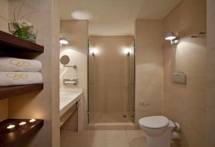 O&B Athens Boutique Hotel bathroom. Gay-friendly hotel with shower, sink, and toilet. Towels with the O&B logo. Modern design.