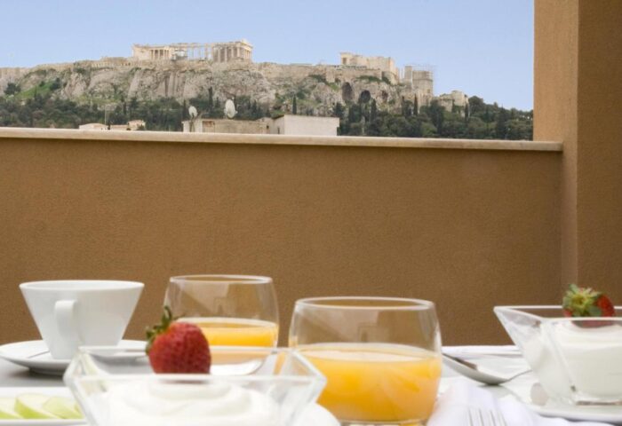 Breakfast with Acropolis view at O&B Athens Boutique Hotel, a gay-friendly hotel. Orange juice, yogurt, and fruit. Athens travel.
