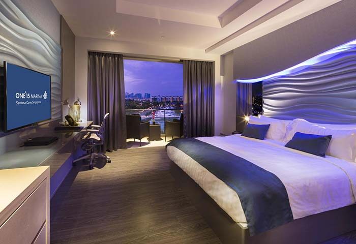 ONE15 Marina Sentosa Cove Singapore gay-friendly hotel room. Balcony view of the marina. Modern design, blue accents, and luxury amenities.