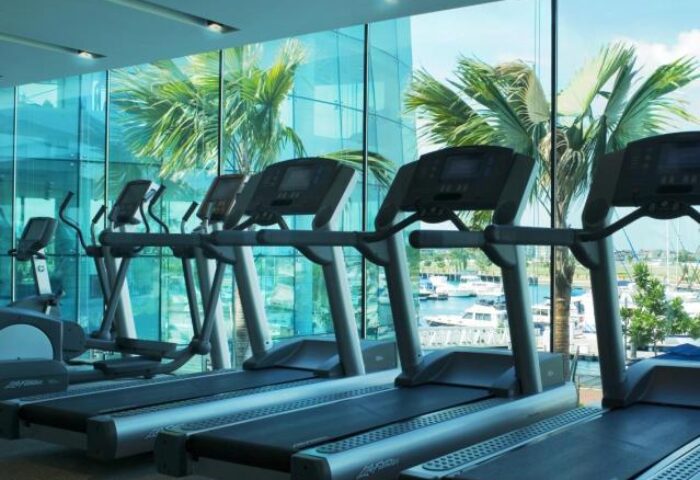 ONE15 Marina Sentosa Cove Singapore gym. Treadmills and ellipticals face a marina view. Gay-friendly hotel fitness for active travelers.