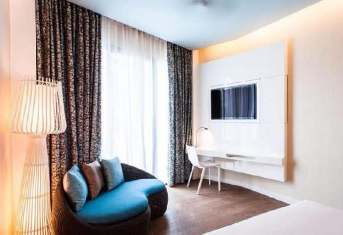 OZO Chaweng Samui gay-friendly hotel room. Modern interior, blue couch, TV, and desk. Ideal for gay travelers seeking comfort in Samui.