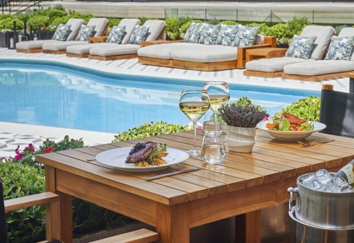 Poolside dining at Oceana Santa Monica, LXR Hotels & Resorts, a gay-friendly hotel. Loungers, drinks, and food create a relaxing atmosphere.