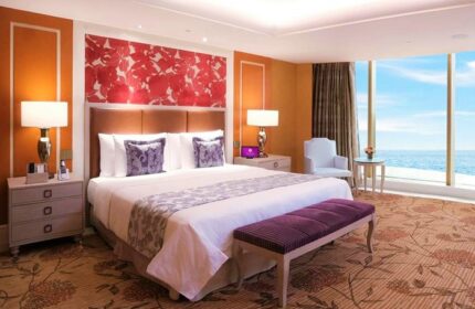 Okada Manila gay-friendly hotel room. Luxurious bedroom with ocean view, king-size bed, and purple accents. Upscale travel for gay men.