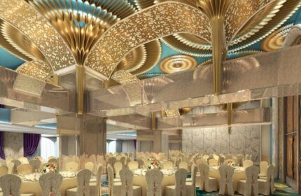 Okada Manila's gay-friendly hotel ballroom. The event space features round tables with floral centerpieces and an ornate gold ceiling.