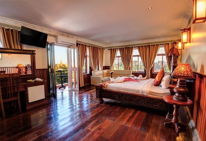 Okay Boutique Hotel room. Gay-friendly hotel with dark wood floors, balcony, bed, and seating area. Ideal for gay men travel.