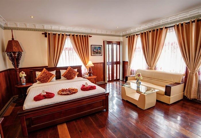 Okay Boutique Hotel gay-friendly room. Dark wood floors, bed with decorative towels, and sofa. Ideal for gay men travel.