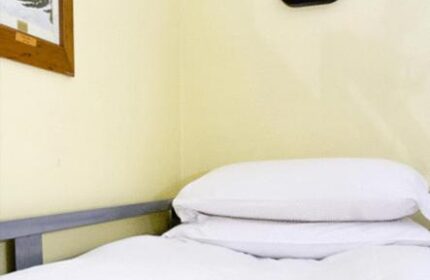 Oliver St. John Gogarty's Hostel room. Dublin gay-friendly hotel with white linens, pillows, and a wall-mounted light fixture. Budget travel.