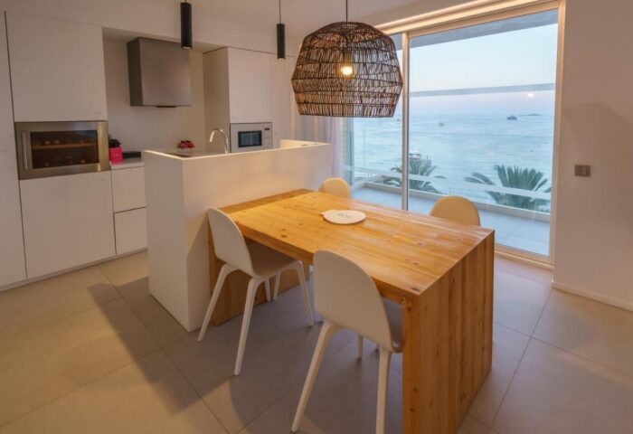 Dining area at One Ibiza Suites, a gay-friendly hotel. Modern kitchen, wood table, and ocean view. Perfect for gay travel in Ibiza.