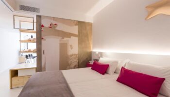 One Ibiza Suites gay-friendly hotel room. Modern design, white bedding with pink accents. Stylish, comfortable stay in Ibiza.