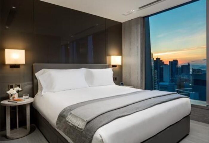 One96, a gay-friendly hotel: Modern room with a large window overlooking the city skyline at sunset. A luxurious travel experience.