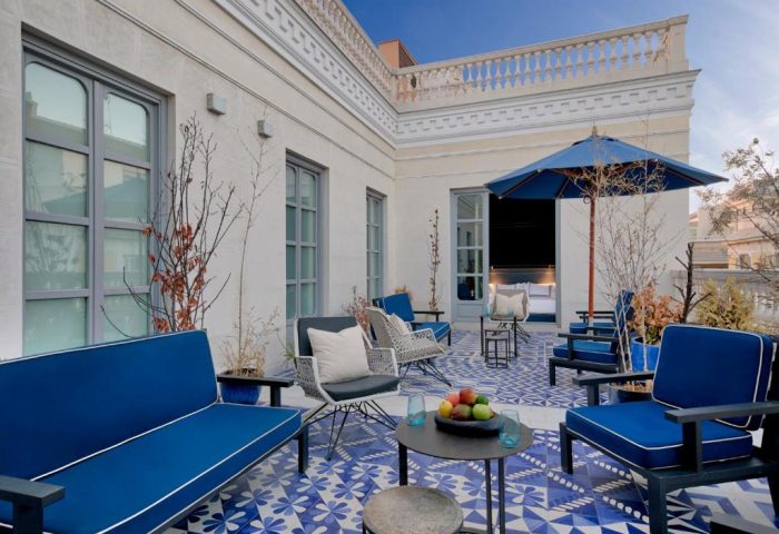 Only YOU Hotel Atocha's terrace, a gay-friendly boutique hotel in Madrid. Blue & white patterned floor, seating area, umbrella, and open room.