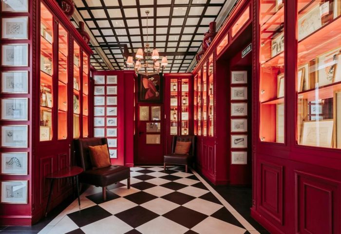 Interior of Only YOU Boutique Hotel Atocha, a gay-friendly hotel in Madrid. Red walls, checkered floor, seating area, and artwork.