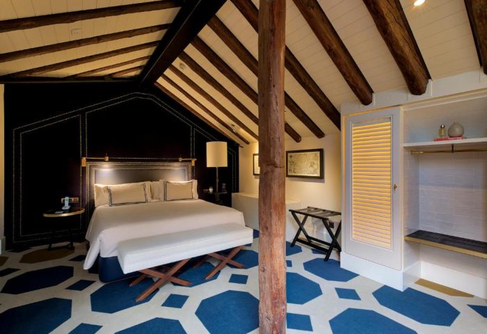 Only YOU Boutique Hotel Atocha's gay-friendly room. Madrid hotel interior with bed, wooden beams, and blue geometric carpet.
