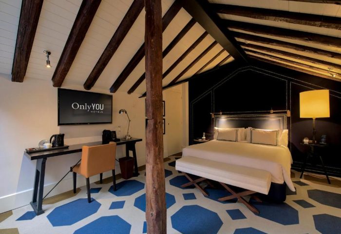 Only YOU Hotel Atocha Madrid, gay-friendly boutique hotel. Bedroom with desk, bed, and exposed beams. Stylish gay travel accommodation.