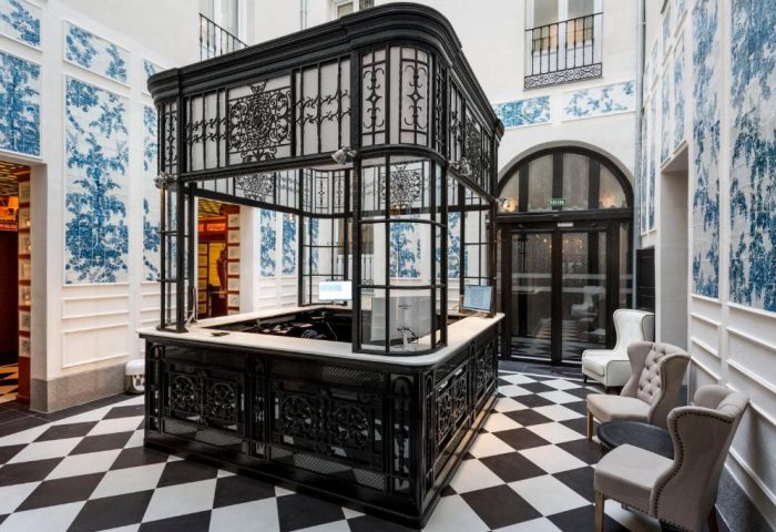 Only YOU Hotel Atocha's reception area. Gay-friendly boutique hotel in Madrid with black and white checkered floor and blue floral wallpaper.