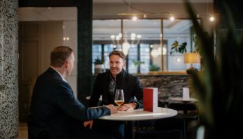 Two men chatting at a table in the stylish lounge of the gay-friendly Opus Hotel. The hotel offers a welcoming and inclusive atmosphere for gay travelers.