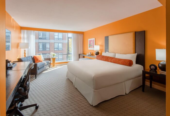 Opus Hotel room. Gay-friendly hotel with orange walls, king bed, desk, and sofa. Modern design for gay men's travel in Vancouver.