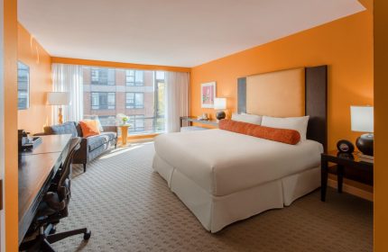 Opus Hotel room. Gay-friendly hotel with orange walls, king bed, desk, and sofa. Modern design for gay men's travel in Vancouver.