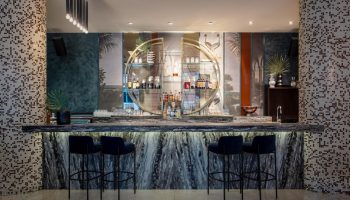Opus Hotel bar. Gay-friendly hotel featuring a stylish bar with marble counter, blue stools, and unique shelving. Great for gay travel.