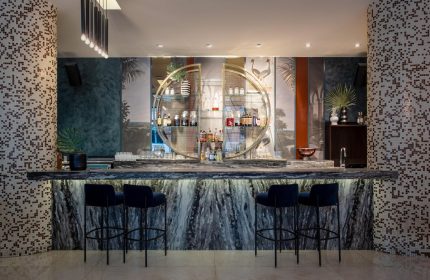 Opus Hotel bar. Gay-friendly hotel featuring a stylish bar with marble counter, blue stools, and unique shelving. Great for gay travel.