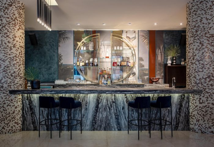 Opus Hotel bar. Gay-friendly hotel featuring a stylish bar with marble counter, blue stools, and unique shelving. Great for gay travel.